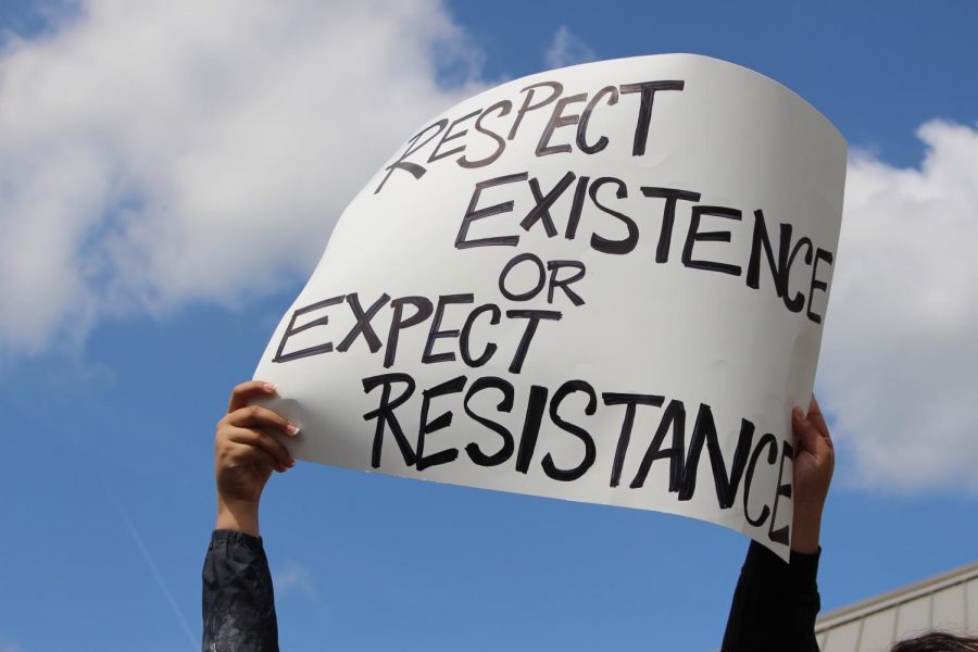 A poster above the crowd reading Respect existence or expect resistance.