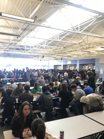 The cafeteria is crowded as students wait in line for lunch.