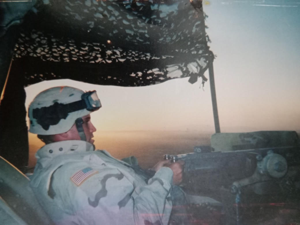 My uncle in Iraq, mounting an M249 in the early morning.